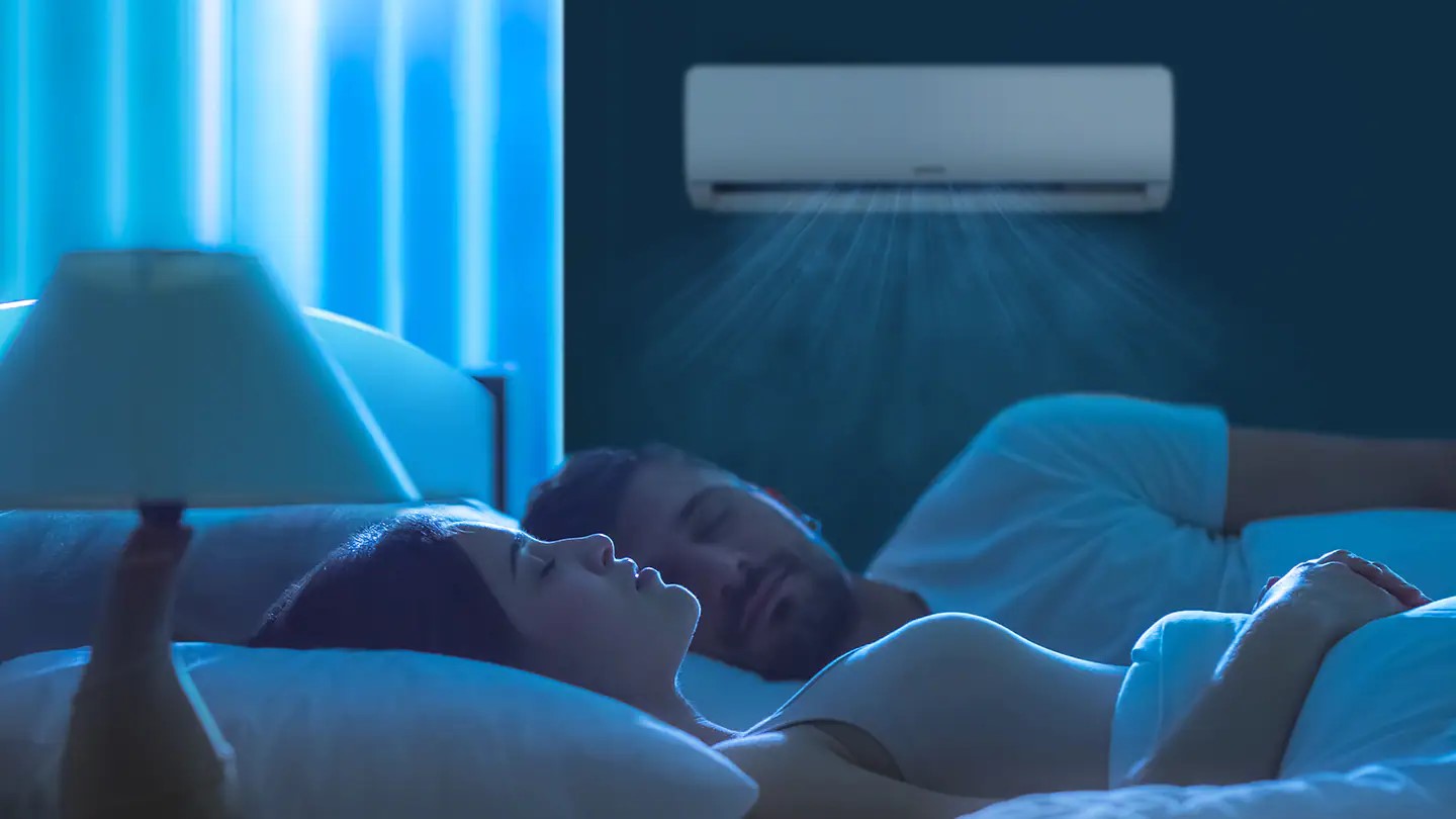 Couple endormi dans une chambre, l'unité intérieure en fonctionnement au mur